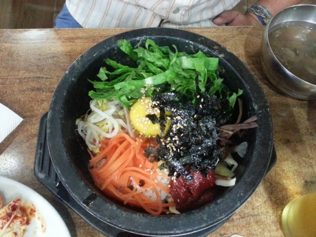 Dolsot bibimbap is served in a sizzling hot stone pot. The raw egg starts to cook when you mix everything together.