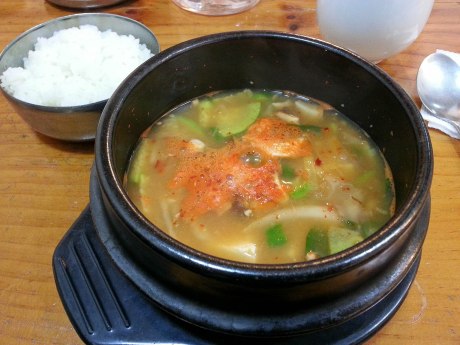 Doenjang jjigae is served sizzling hot in a stone bowl along with a side of rice. 